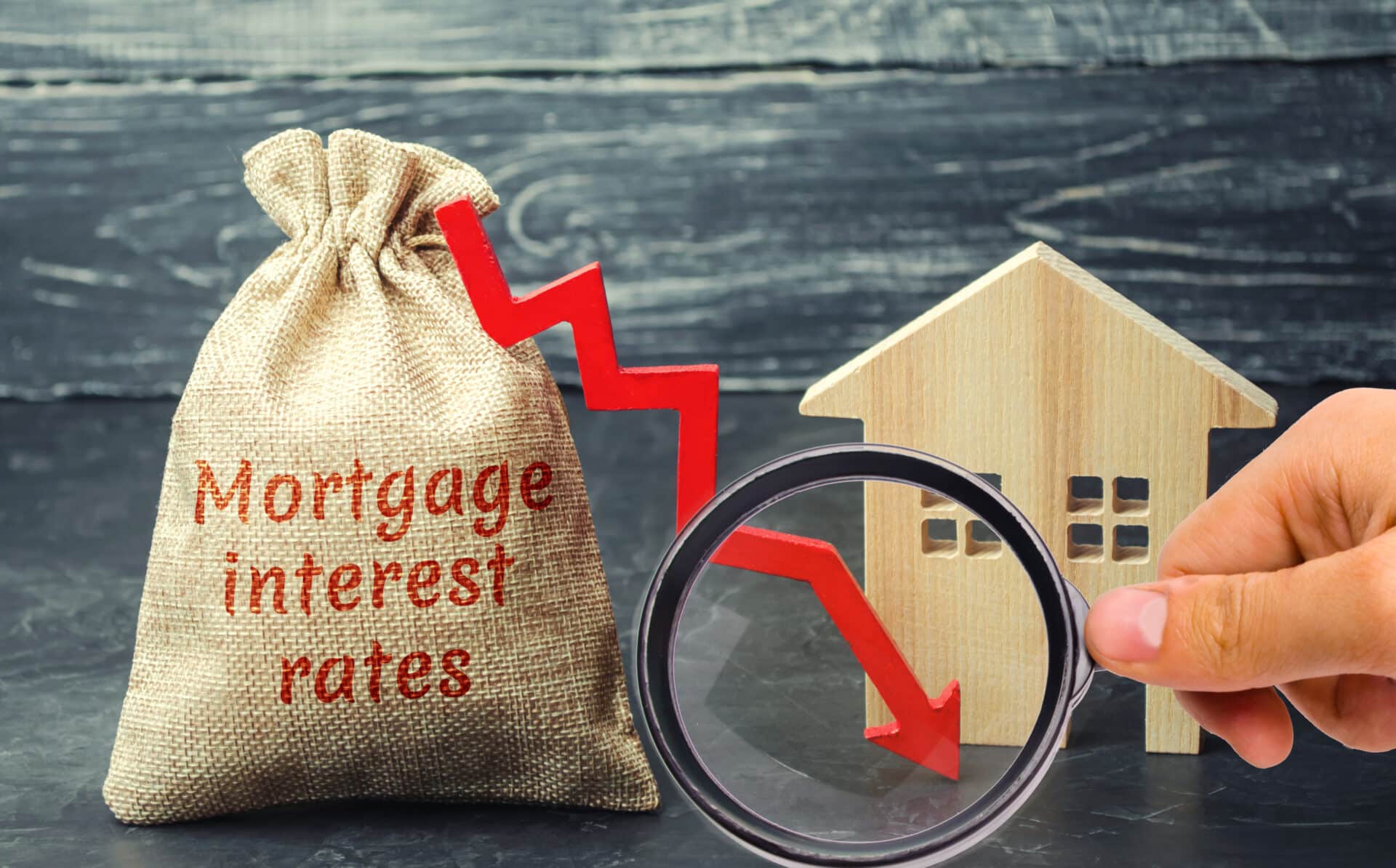 Bag with the money and the word Mortgage interest rates and arrow to down and house. Low interest in mortgages. Reducing interest payments for mortgages. The fall in housing rates on credit. Low housing demand